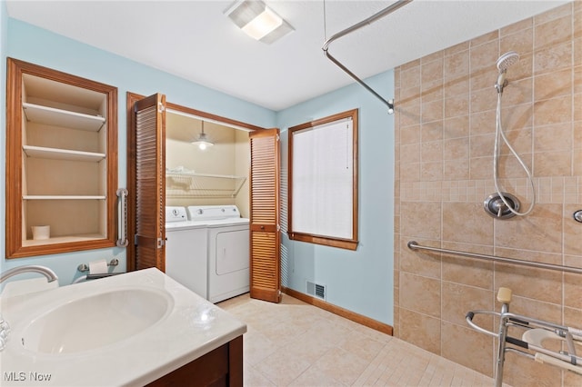 bathroom featuring washer and dryer, a tile shower, built in features, and vanity