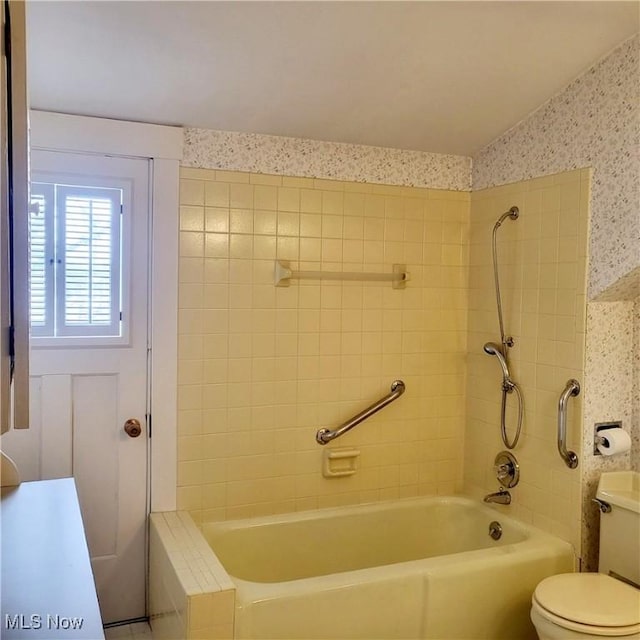 bathroom with tiled shower / bath combo and toilet