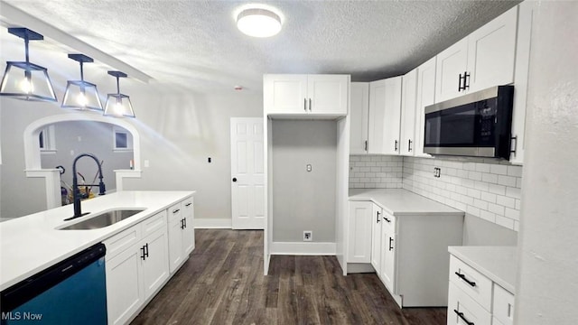 kitchen featuring white cabinetry, dishwasher, hanging light fixtures, and sink