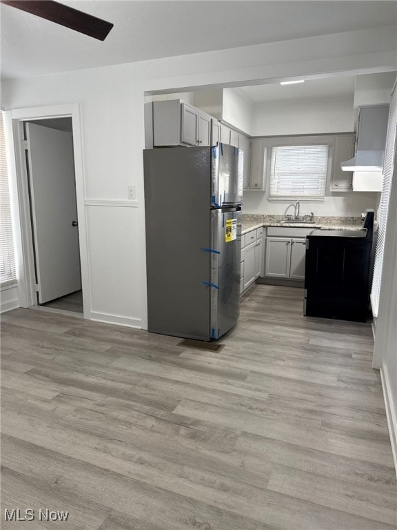 kitchen featuring gray cabinetry, sink, black / electric stove, stainless steel fridge, and light wood-type flooring