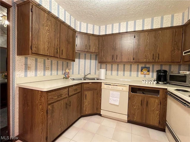 kitchen featuring a textured ceiling, sink, light tile patterned flooring, and white appliances