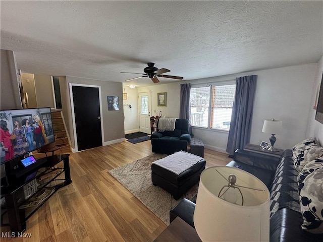 living room featuring a textured ceiling, light wood-type flooring, and ceiling fan