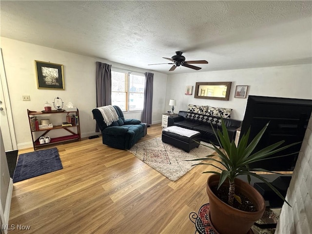 living room with a textured ceiling, hardwood / wood-style flooring, and ceiling fan