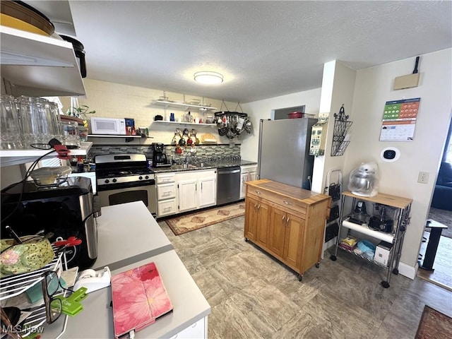 kitchen with appliances with stainless steel finishes, a textured ceiling, and white cabinetry