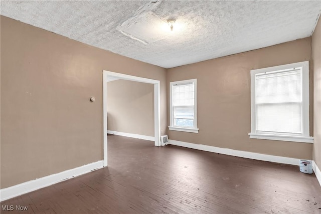 empty room featuring dark wood-type flooring and a textured ceiling