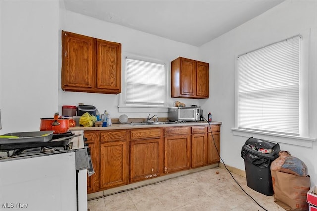 kitchen with white gas range oven, a healthy amount of sunlight, and sink