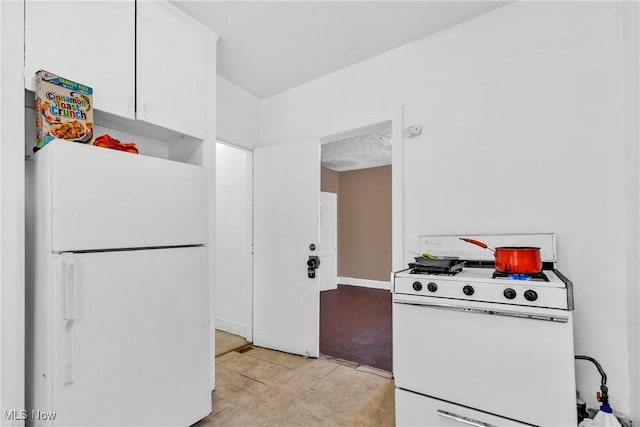 kitchen featuring white cabinetry, light tile patterned flooring, and white appliances