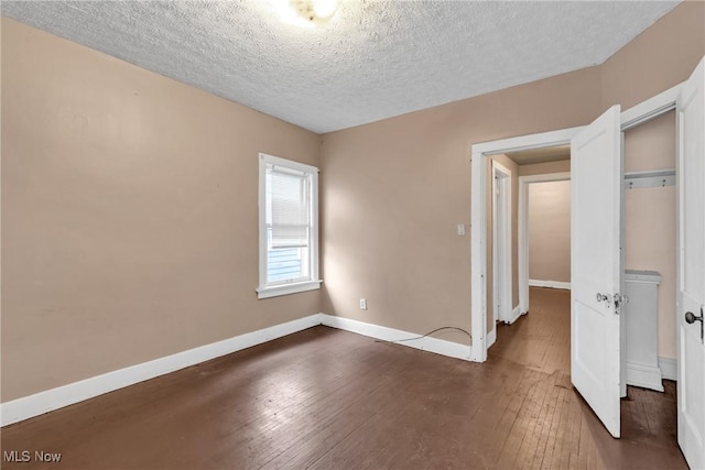 unfurnished bedroom featuring a textured ceiling, dark hardwood / wood-style floors, and a closet