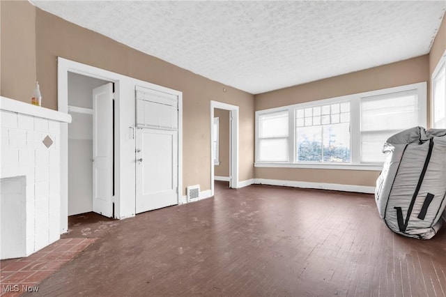 interior space featuring a tiled fireplace, dark wood-type flooring, and a textured ceiling