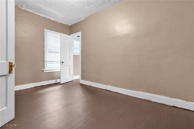 unfurnished room featuring dark hardwood / wood-style floors and a textured ceiling