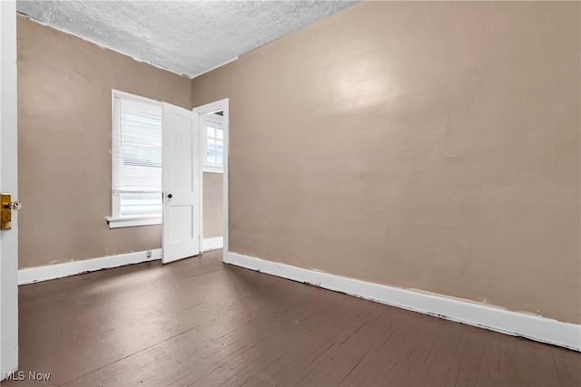 spare room featuring dark hardwood / wood-style floors and a textured ceiling