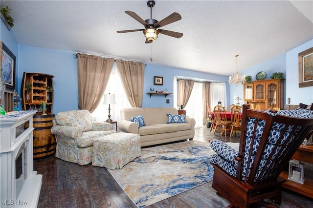 living room with ceiling fan with notable chandelier, dark wood-type flooring, a wealth of natural light, and vaulted ceiling