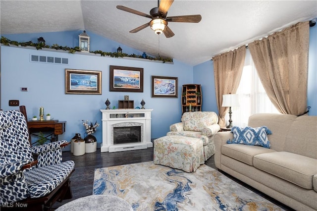 living room featuring a high end fireplace, a textured ceiling, vaulted ceiling, ceiling fan, and dark wood-type flooring