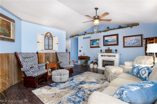 living room with ceiling fan, vaulted ceiling, a fireplace, and dark wood-type flooring