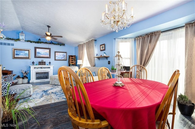 dining room with a textured ceiling, ceiling fan with notable chandelier, and lofted ceiling