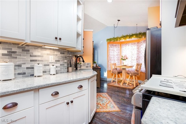 kitchen with white cabinets, stainless steel fridge, sink, and vaulted ceiling