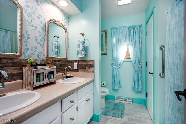 bathroom featuring backsplash, vanity, a textured ceiling, and toilet