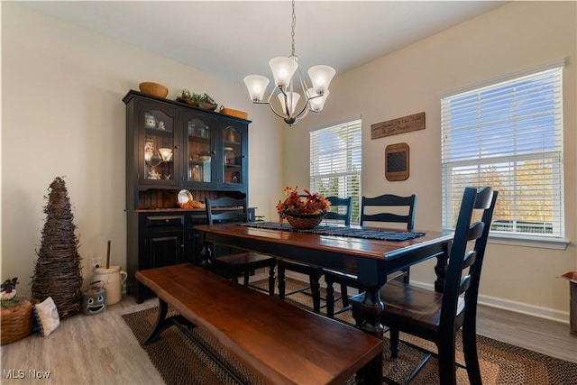 dining room with a wealth of natural light, hardwood / wood-style floors, and an inviting chandelier