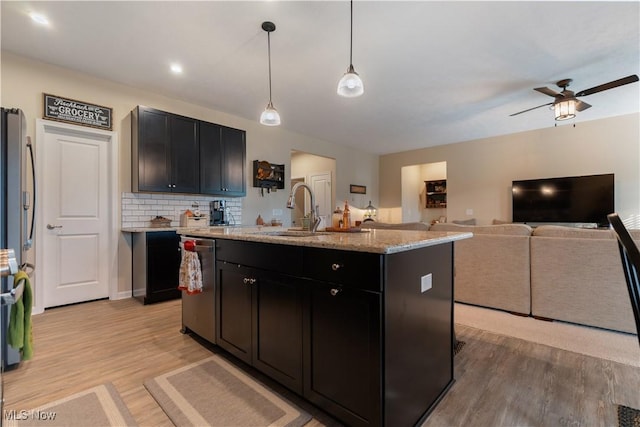 kitchen with pendant lighting, backsplash, a center island with sink, sink, and stainless steel appliances