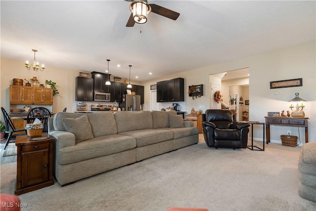 living room featuring ceiling fan with notable chandelier and light colored carpet