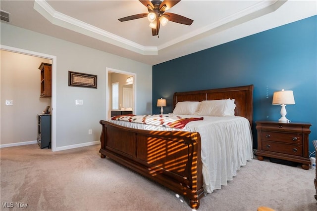 carpeted bedroom with a tray ceiling, ensuite bath, ceiling fan, and crown molding