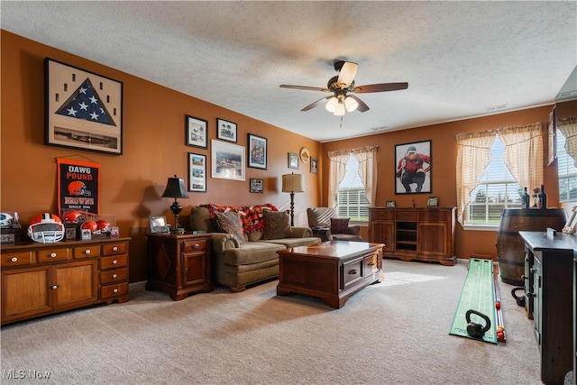 carpeted living room with ceiling fan, a textured ceiling, and a wealth of natural light