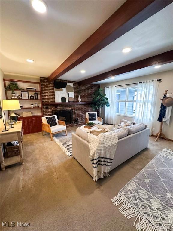 living room featuring beam ceiling, a brick fireplace, and brick wall