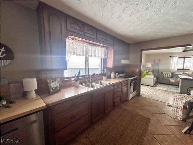 kitchen with light tile patterned floors, white range, a textured ceiling, and sink