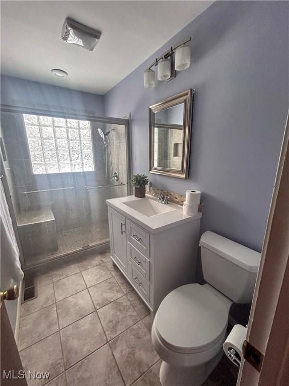 bathroom featuring tile patterned floors, vanity, toilet, and a shower with door