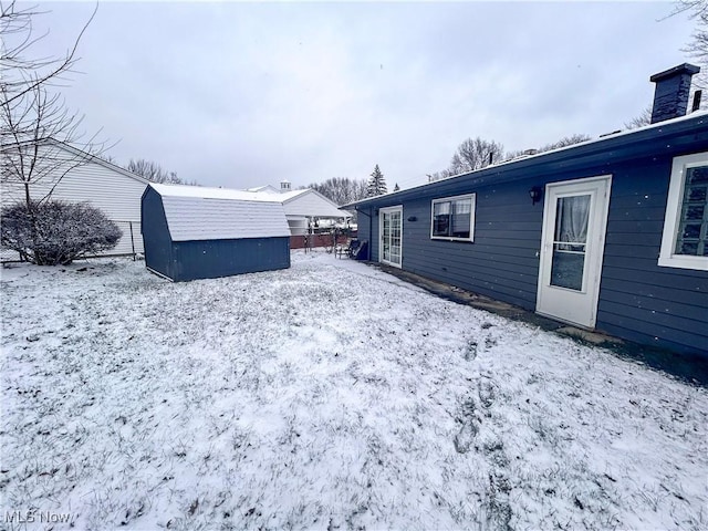 yard layered in snow featuring a storage unit