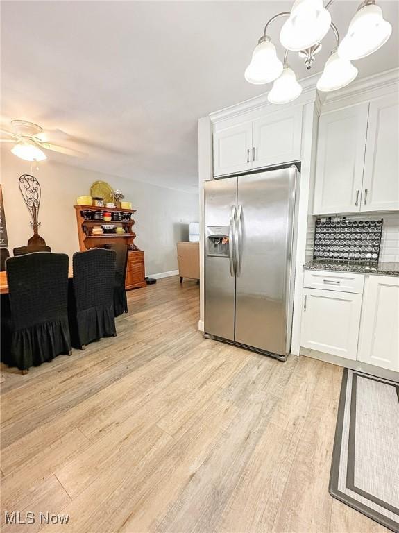 kitchen with white cabinets, ceiling fan with notable chandelier, stainless steel fridge with ice dispenser, and tasteful backsplash