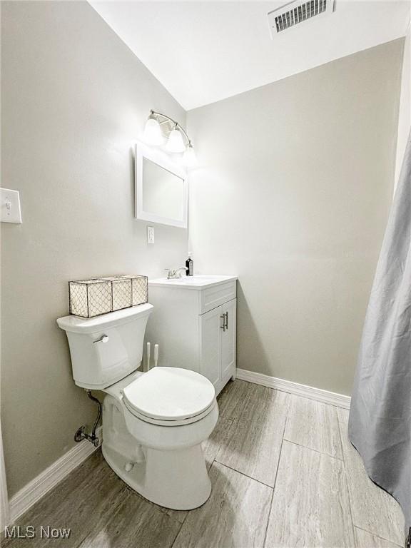 bathroom with wood-type flooring, vanity, and toilet