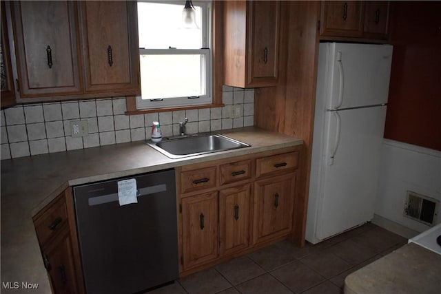 kitchen featuring backsplash, sink, dishwasher, and white refrigerator