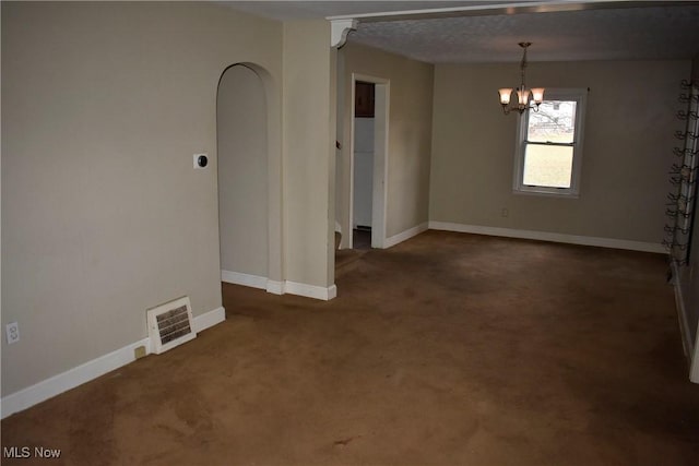 empty room with dark colored carpet and a chandelier