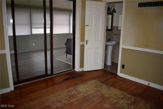 unfurnished bedroom with ensuite bathroom and dark hardwood / wood-style flooring