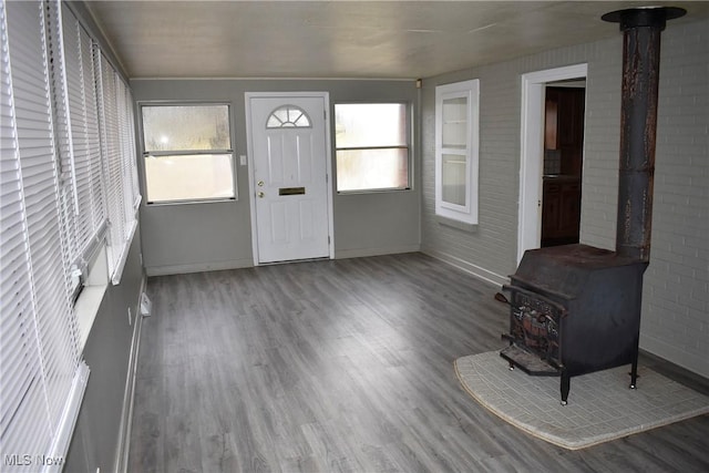 foyer entrance featuring hardwood / wood-style flooring, a wood stove, and plenty of natural light