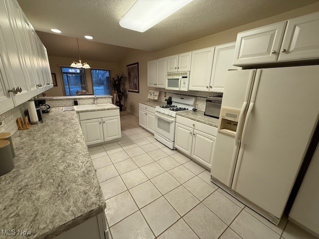 kitchen featuring white cabinetry, sink, hanging light fixtures, a chandelier, and white appliances