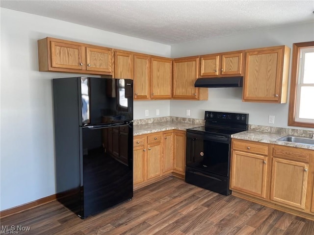 kitchen with sink, dark wood-type flooring, black appliances, and a textured ceiling