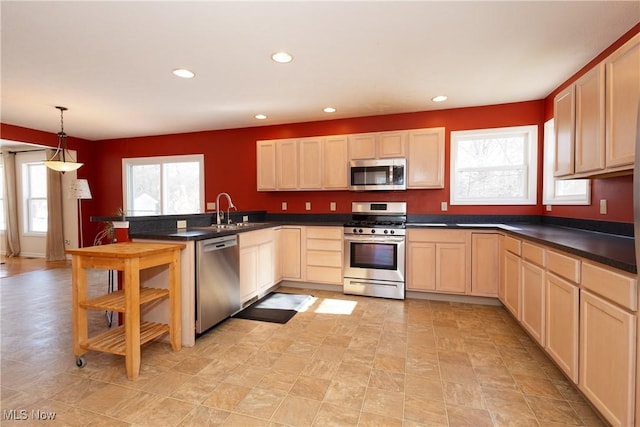 kitchen with hanging light fixtures, light brown cabinets, sink, and appliances with stainless steel finishes