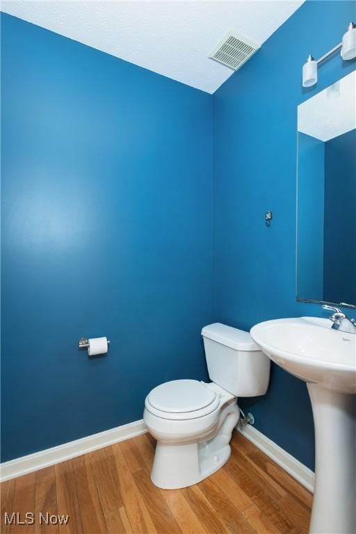 bathroom featuring wood-type flooring and toilet