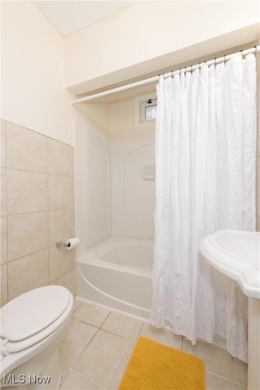 bathroom featuring tile patterned flooring, shower / tub combo, toilet, and tile walls