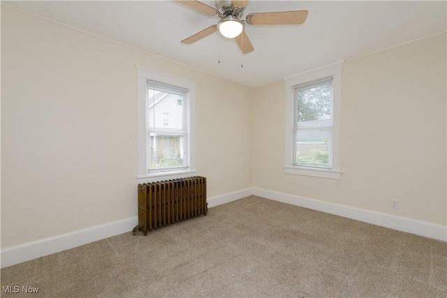 carpeted empty room featuring ceiling fan and radiator heating unit