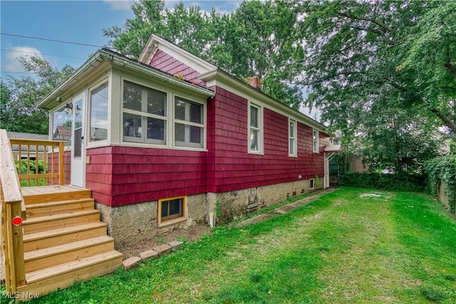 view of property exterior with a sunroom, a deck, and a lawn