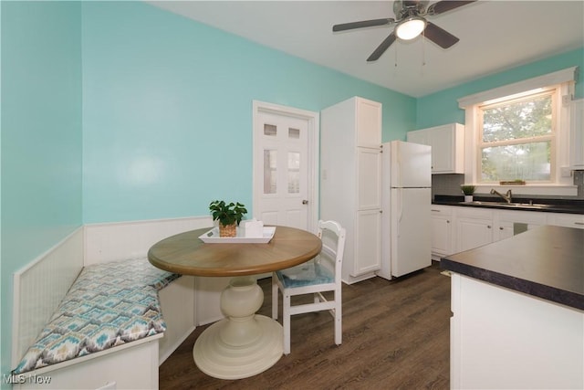 dining area with ceiling fan, sink, and dark wood-type flooring