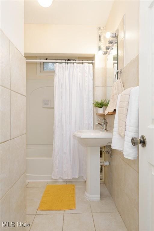 bathroom with shower / bath combo, tile patterned floors, and tile walls