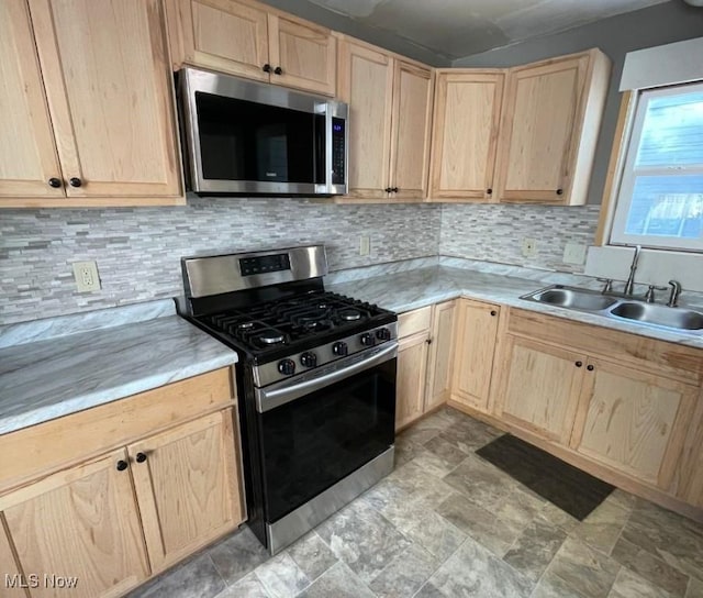 kitchen with decorative backsplash, light brown cabinets, sink, and appliances with stainless steel finishes