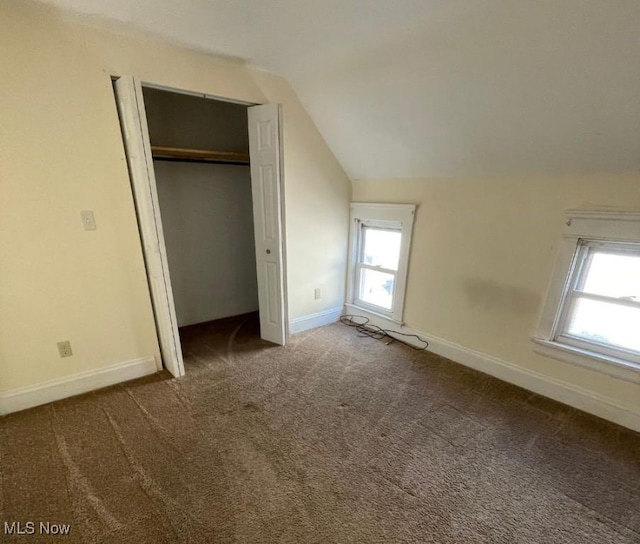 unfurnished bedroom with a closet, carpet, and vaulted ceiling