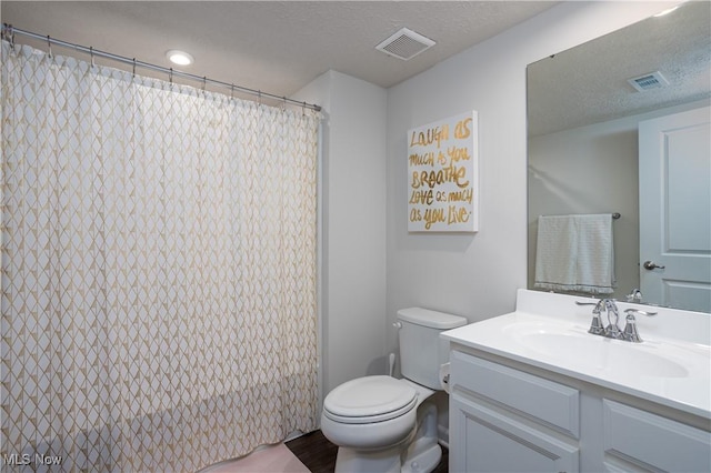 bathroom with vanity, curtained shower, toilet, and a textured ceiling