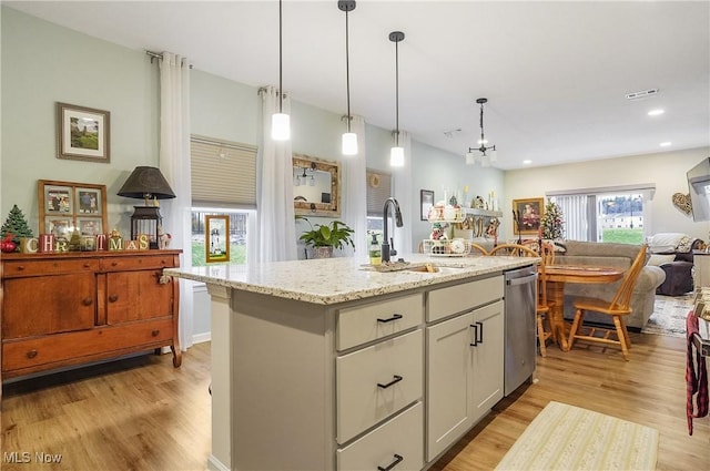 kitchen with decorative light fixtures, a center island with sink, light hardwood / wood-style floors, and sink