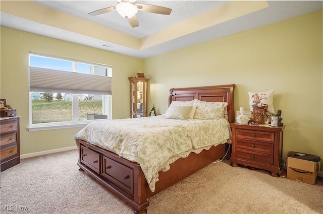 carpeted bedroom featuring a raised ceiling and ceiling fan